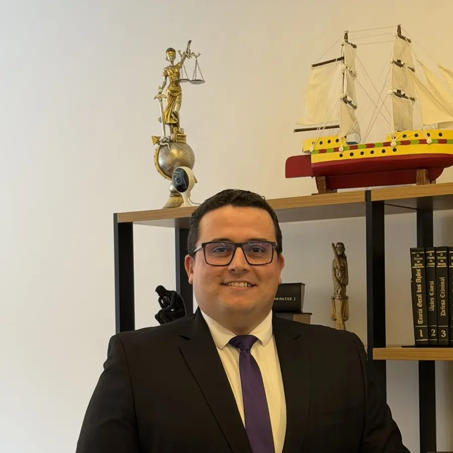 Dr. Sérgio Ruiz em seu escritório, junto à estante com a estatueta de Têmis